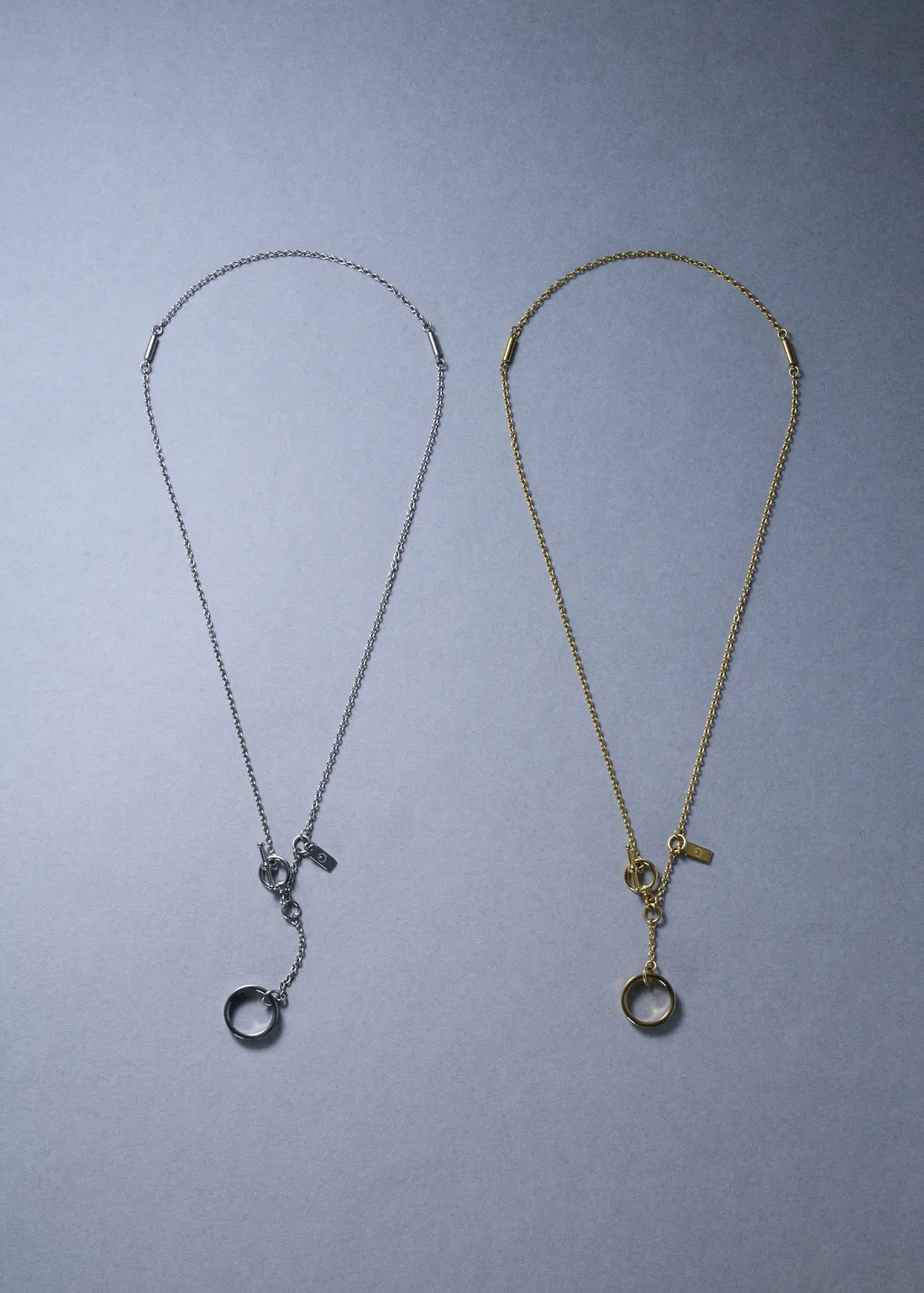 シルバーとゴールドのネックレスの全体。チェーン、マンテル金具、リングのチャーム