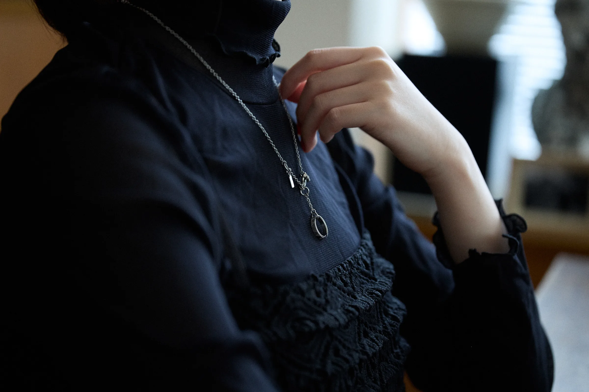 黒いレースのブラウスにシルバーのネックレスを着けた女性