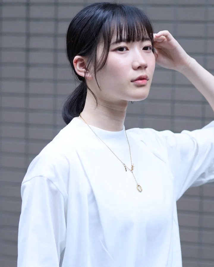 白いTシャツにゴールドのネックレスを着けた女性